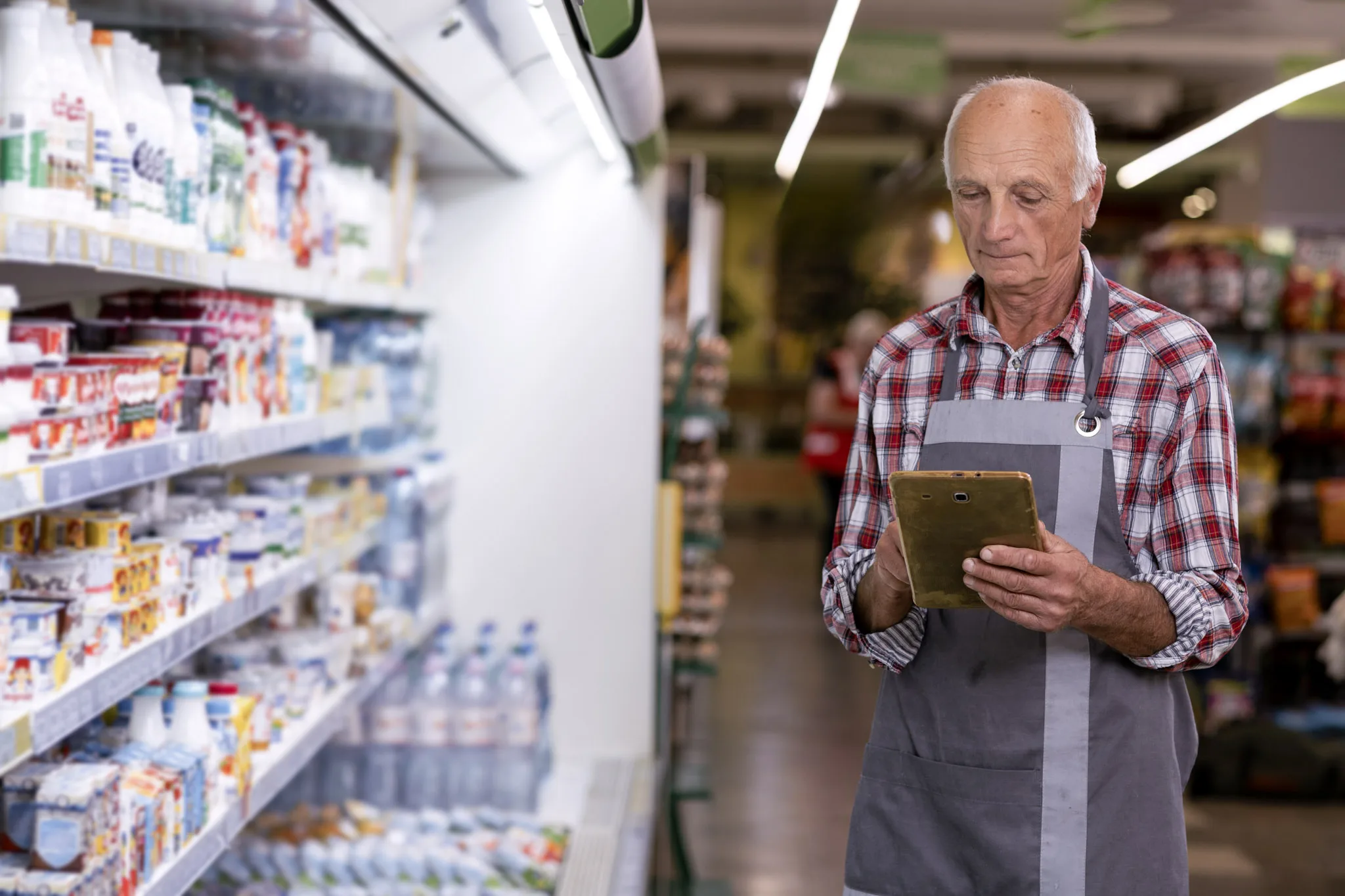 Senior male retail shop owner using a tablet