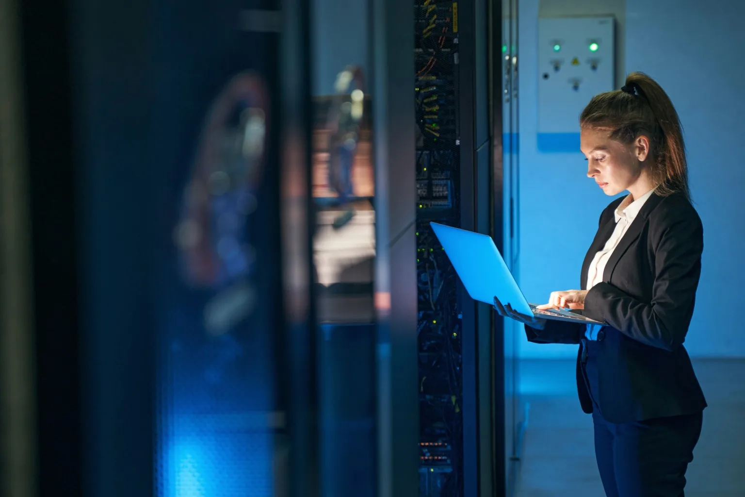 Female engineer working in server room at modern data centre.